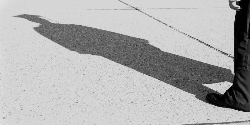 student with shadow wearing graduation robes